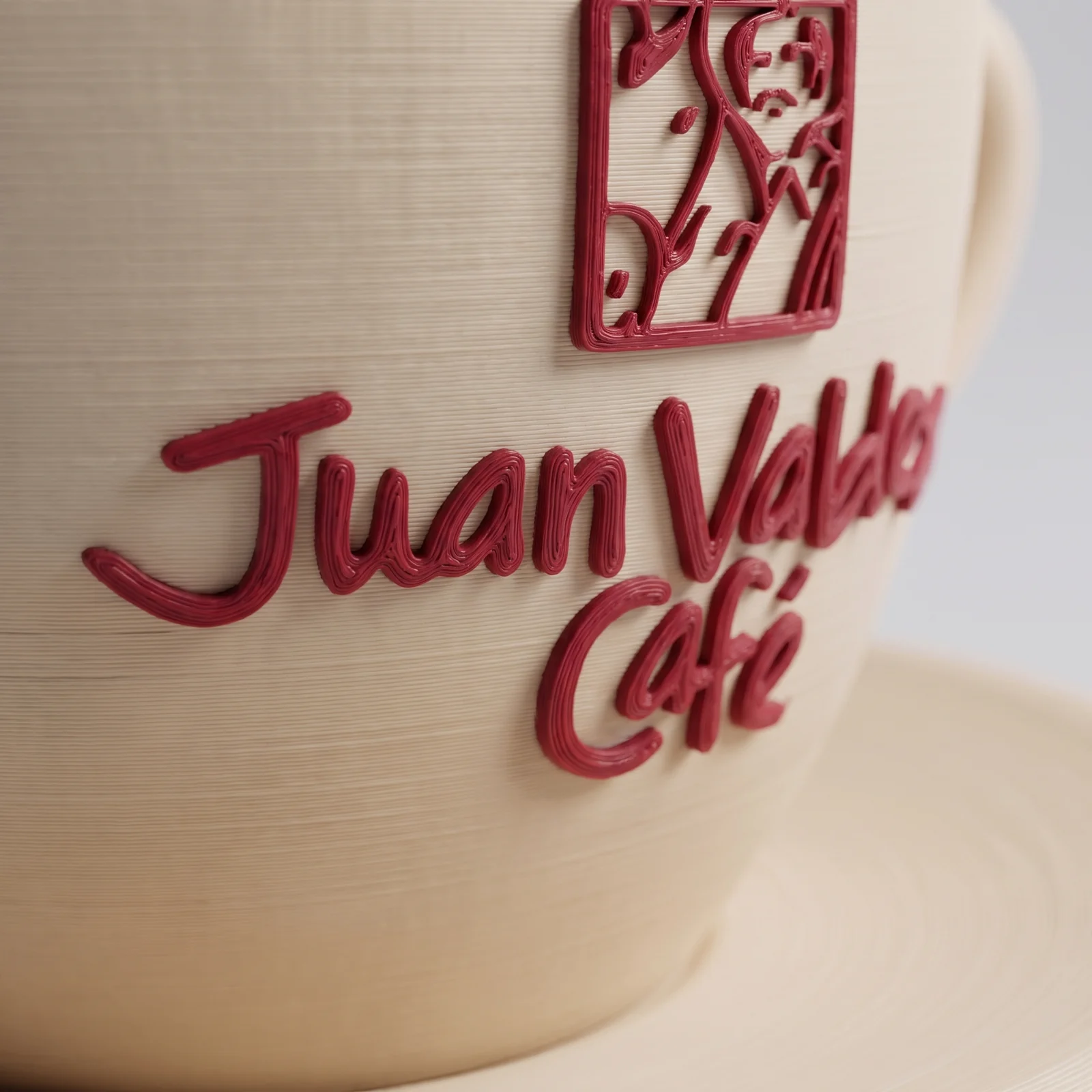 Detalle del logo de Juan Valdez en relieve rojo sobre la taza